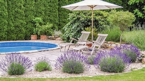 A backyard with a swimming pool, two white lounge chairs, and a large umbrella. - Nice apartment for 6 guests with pool, WIFI, TV and patio (Zábreh)