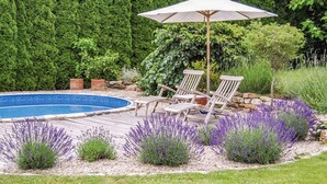 A backyard with a swimming pool, two lounge chairs, and a patio umbrella. - Lovely apartment for 4 people with pool, WIFI and patio (Zábreh)