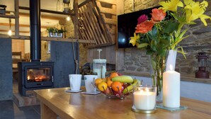 A cozy room with a fireplace, a wooden table with fruit, candles, and a vase with flowers. - 4 bedroom accommodation in Llanboidy, near Laugharne (Llanboidy, near Laugharne)