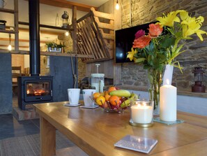 A cozy room with a fireplace, a wooden table with fruit, candles, and a vase with flowers. - 4 bedroom accommodation in Llanboidy, near Laugharne (Llanboidy, near Laugharne)