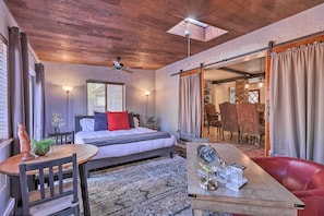 Relax in this inviting bedroom with a large bed, wooden ceiling fan, and skylight, perfect for a cozy dining experience.