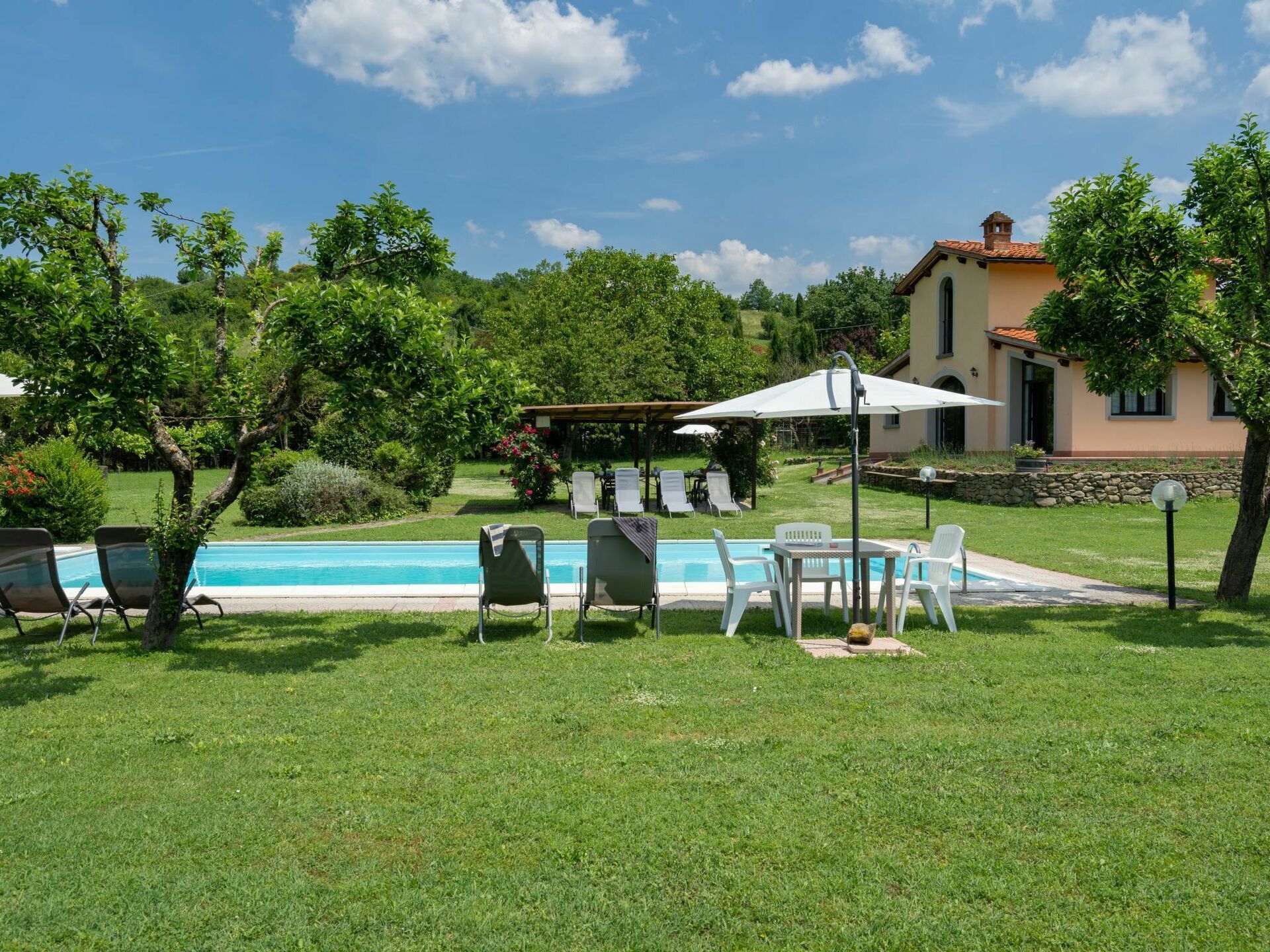 A pool area with lounge chairs and a pergola.