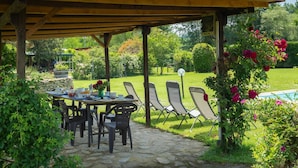 An outdoor patio with a table set for dining, surrounded by chairs, and a covered area with a view of a garden and pool. - Wonderful private villa for 4 guests with pool, WIFI, TV and pets allowed (Terranuova Bracciolini)