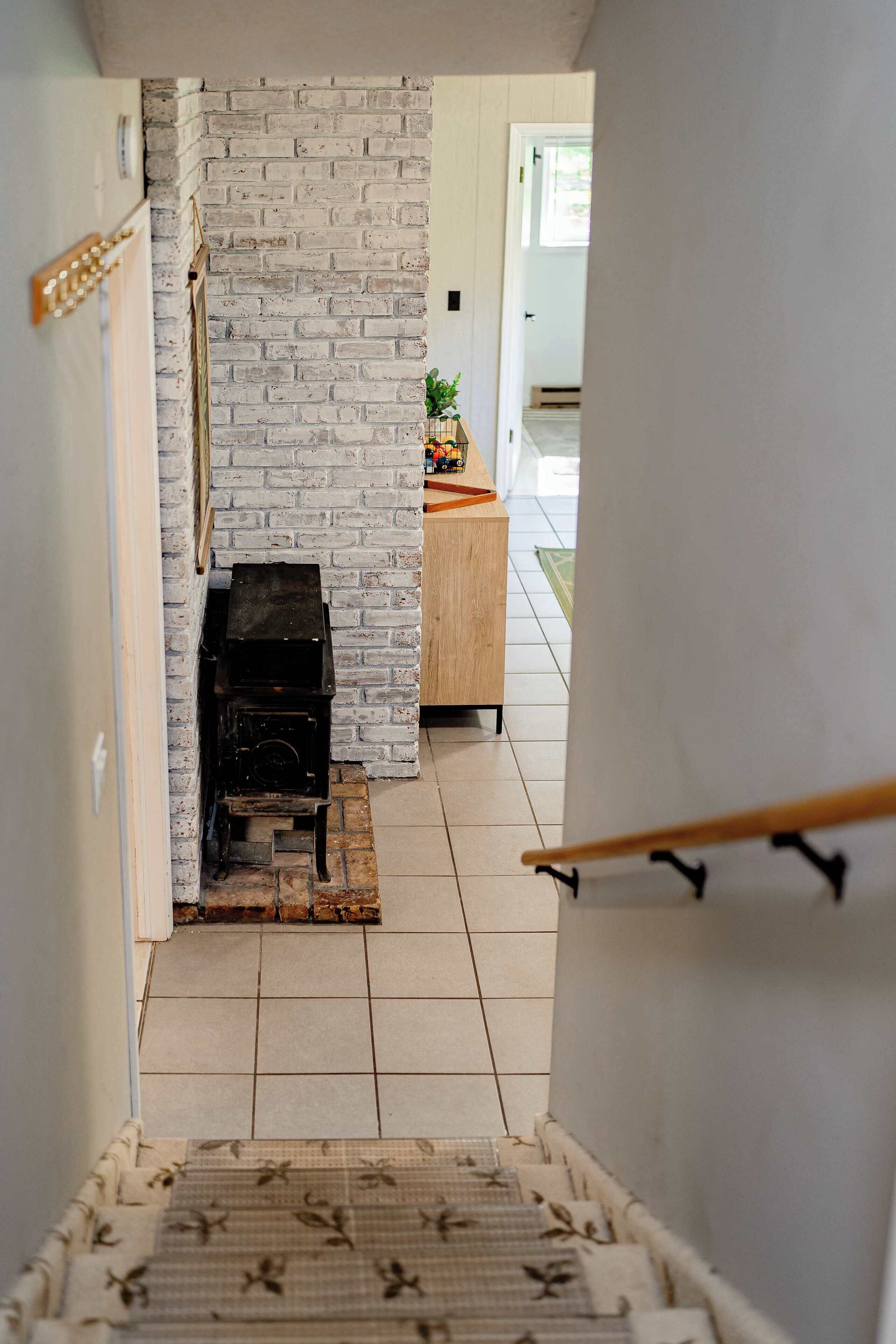 Una escalera que conduce a una habitación con una pared de ladrillo y una chimenea.