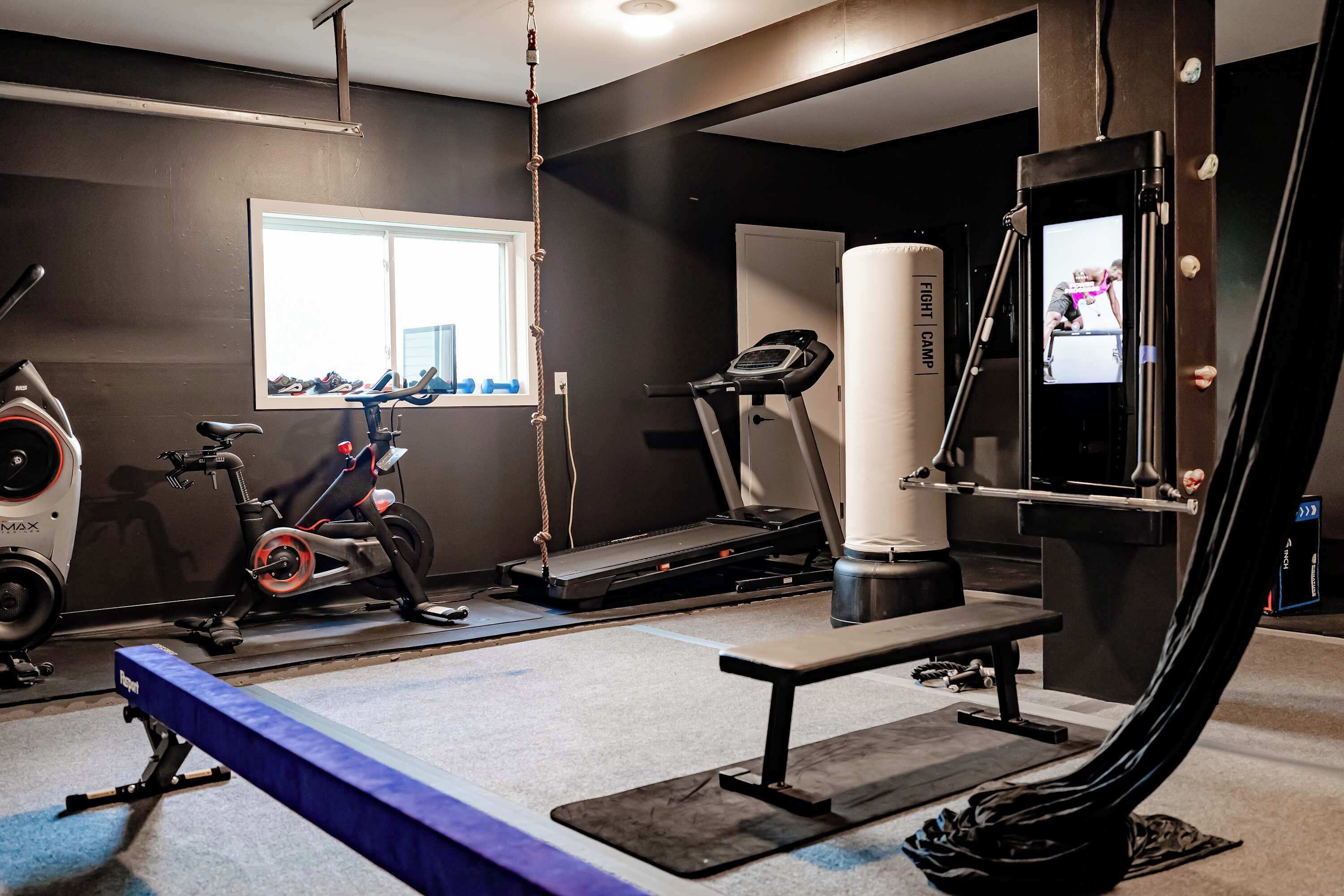 A gym with exercise equipment, a bench, and a punching bag.
