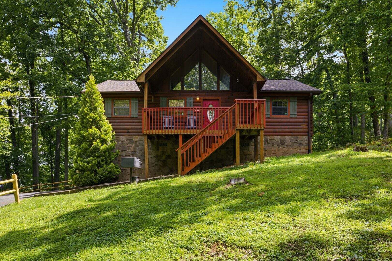 A log cabin with a balcony, surrounded by trees.
