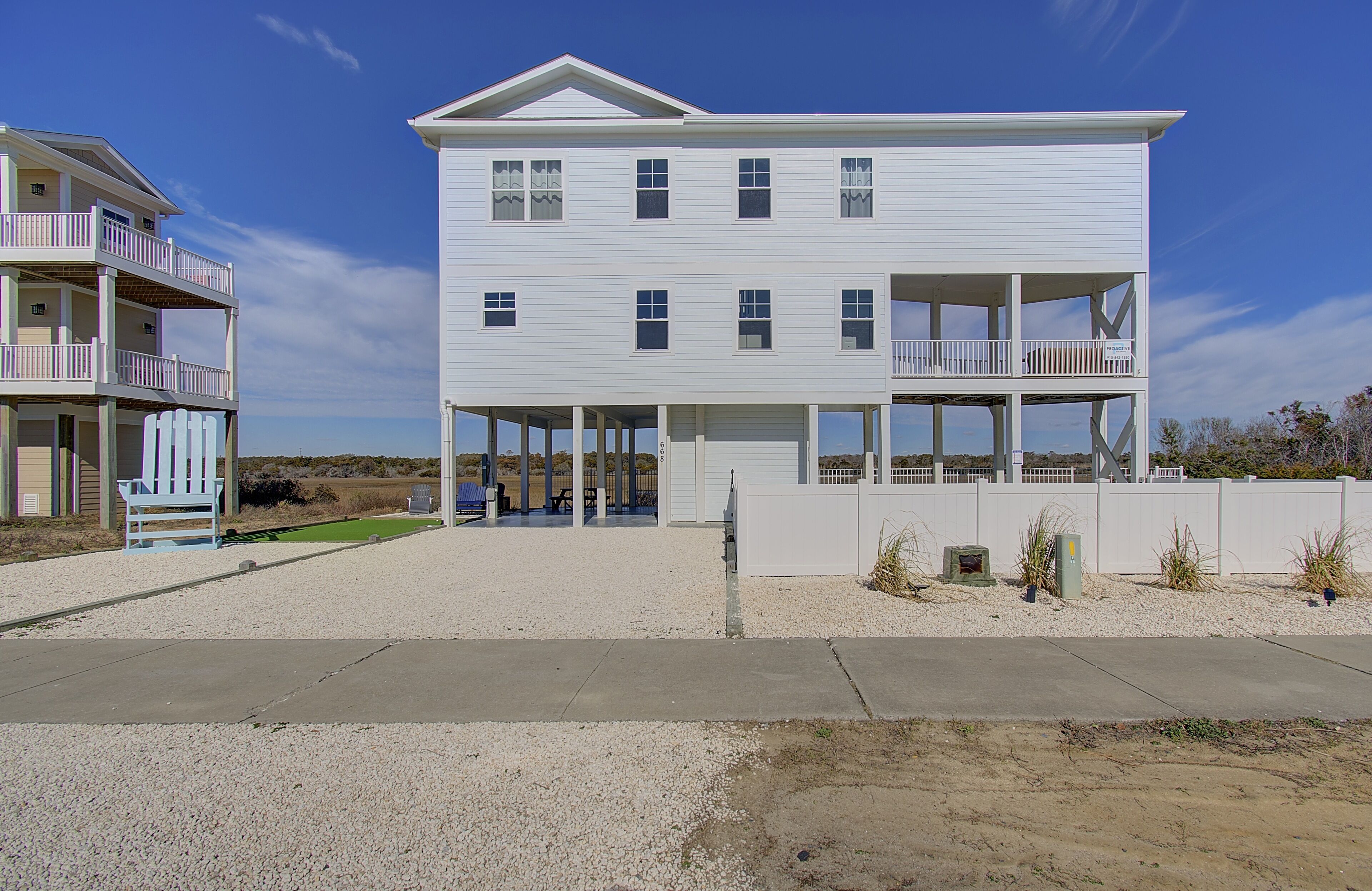 A two-story beachfront property with a covered porch and a balcony.