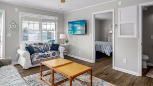 A living room with a ceiling fan, a sofa, a coffee table, and a TV mounted on the wall.