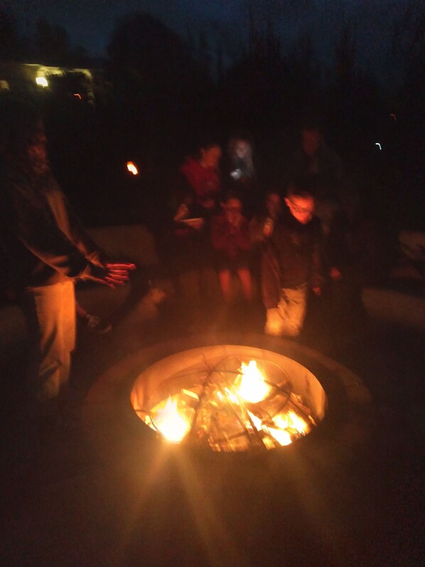 A group of people gathered around a fire pit in a dimly lit outdoor area.