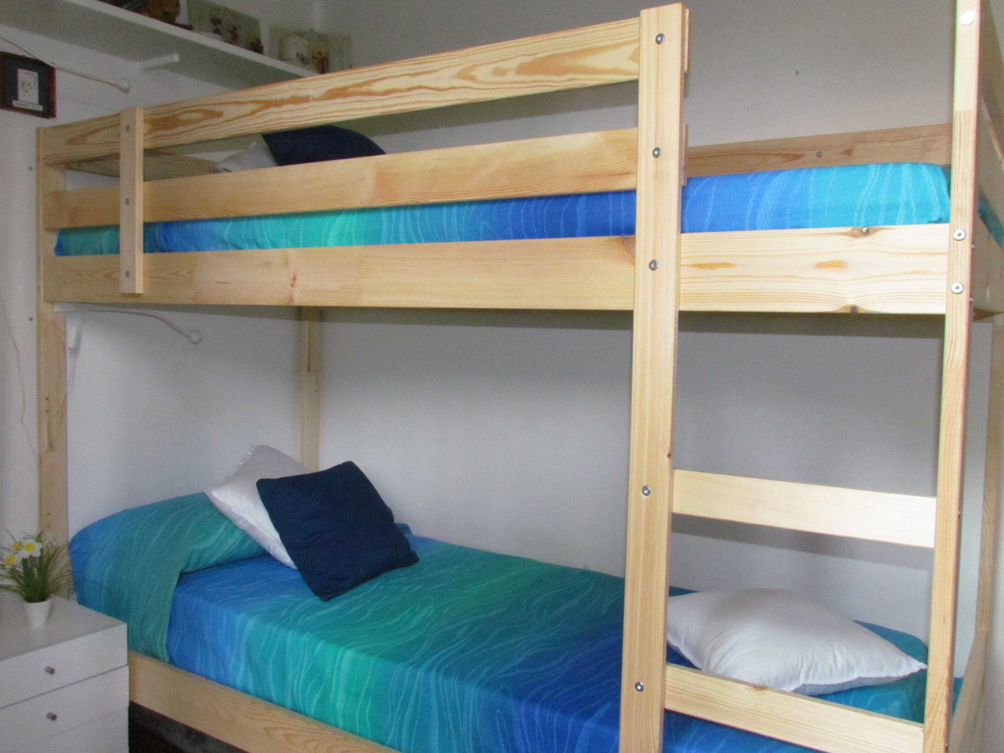 A bunk bed with two levels, each with a pillow and a blue bedspread.