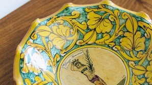 Eine dekorative Keramikschale mit aufwendigen floralen Mustern und einem zentralen Wappen.