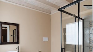 Een moderne badkamer met een houten vloer, een douchecabine van glas, een wit wastafelmeubel en een toilet.