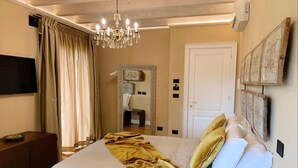 Een slaapkamer met een bed, een kroonluchter, een televisie en kunst aan de muur.