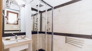 Une salle de bain moderne avec une douche à parois de verre, un lavabo avec un miroir et un porte-serviettes.