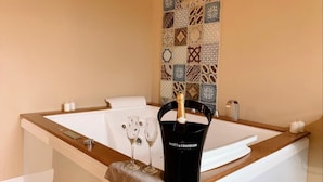 Eine Badewanne mit Eiskübel und Gläsern, ein Handtuch und eine Wand mit gemusterten Fliesen.