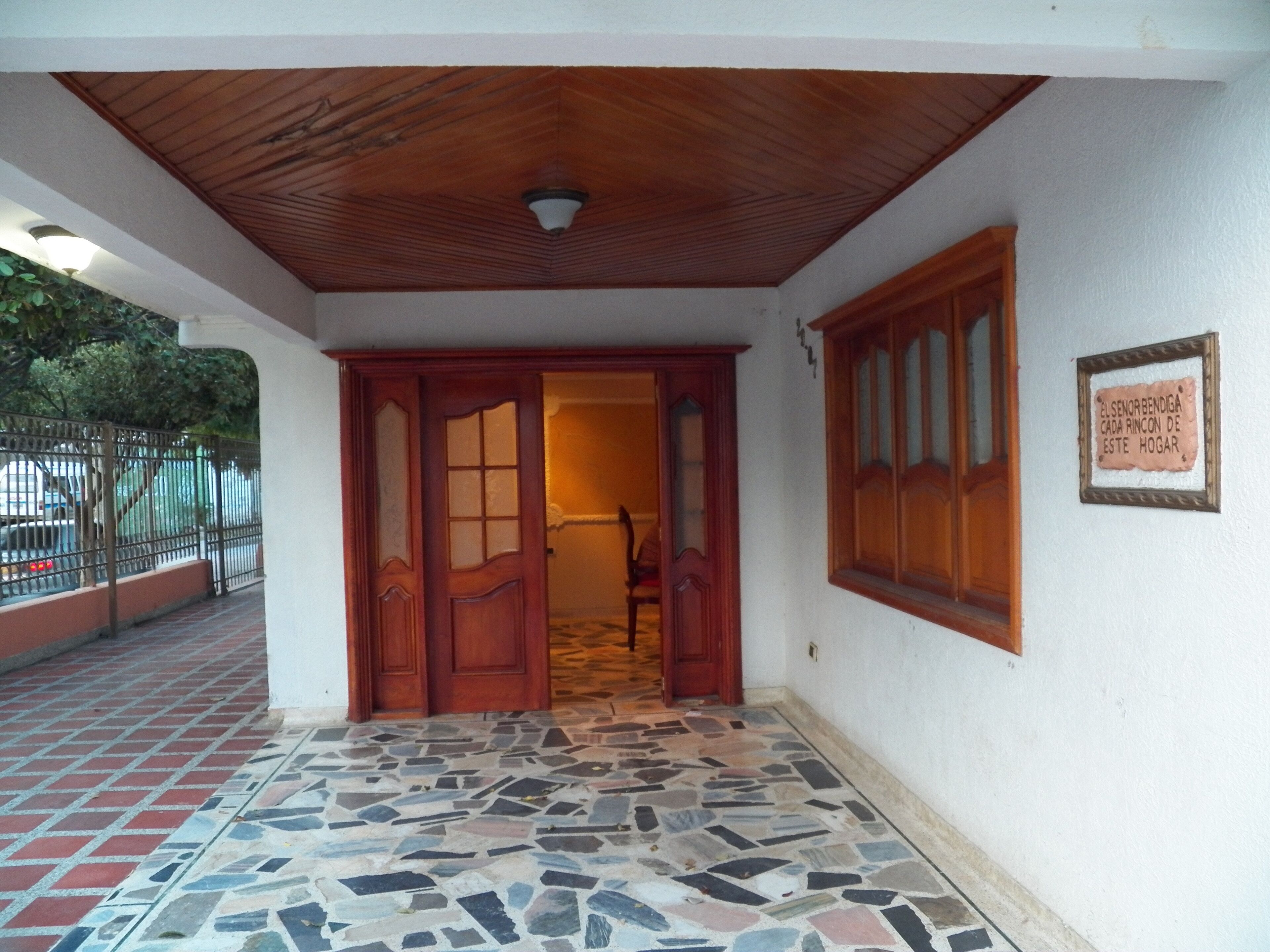 Une entrée d’immeuble avec un sol carrelé, des portes en bois et une enseigne sur le mur.