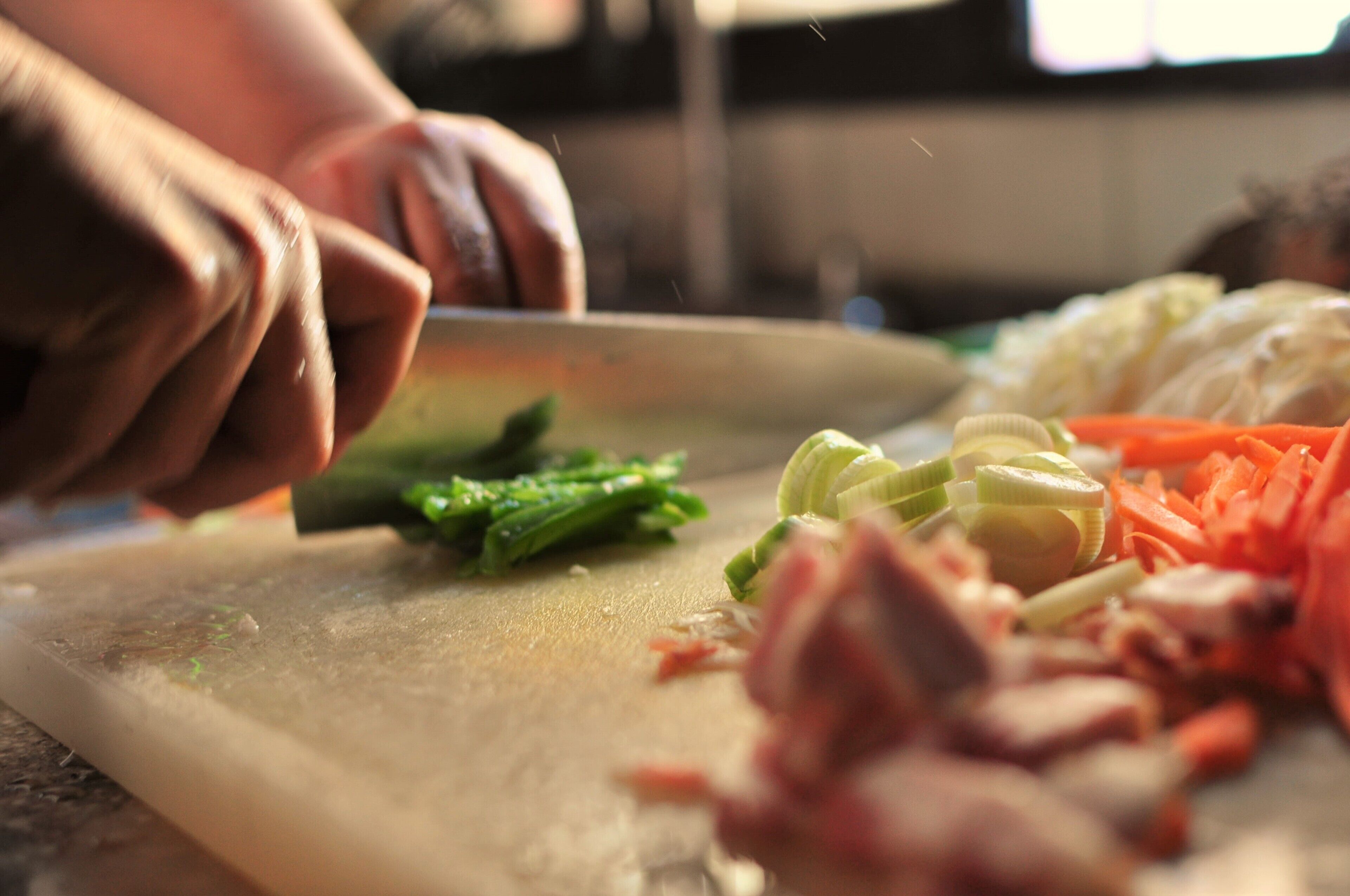 A person chopping vegetables on a cutting board.