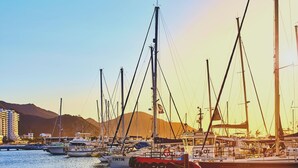 A marina with several boats docked, a clear sky, and a mountainous backdrop. - "hostal Hogar Buenaventura" (Santa Marta)
