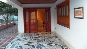 Une entrée d’immeuble avec un sol carrelé, des portes en bois et une enseigne sur le mur.