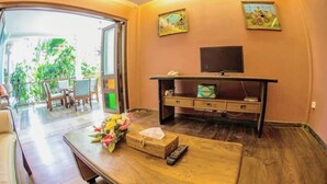 A room with a wooden desk, a television on a stand, and a view of the outdoors. - 2 Bedrooms Vintage Apartment 10 - Balcony,private Kitchen,livingroom,pool (Legian)