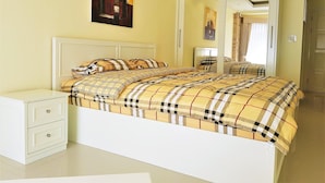 A bedroom with a bed, a nightstand, a mirror, and a painting on the wall.