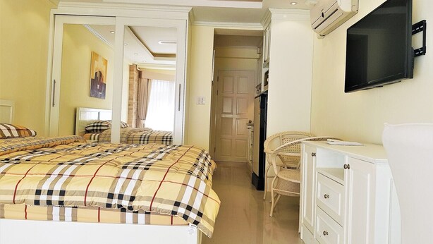 A hotel room with a bed, a television, a wardrobe, and a door leading to another room.