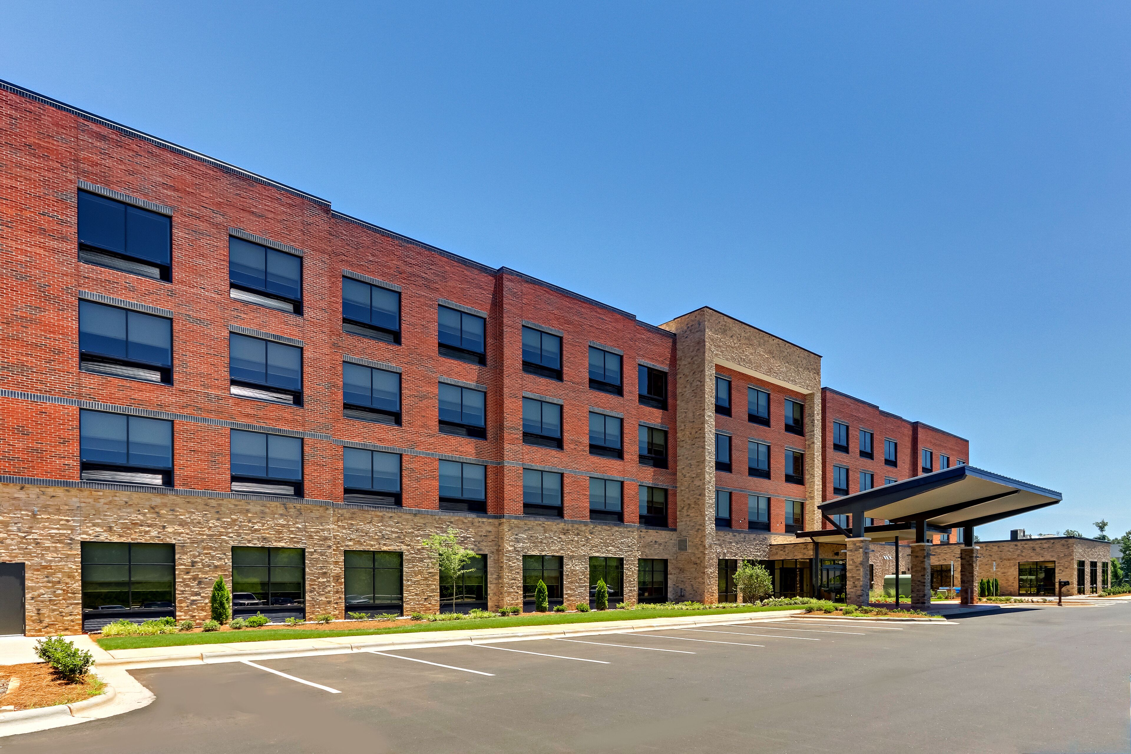 A multi-story brick building with a covered entrance and a parking lot.