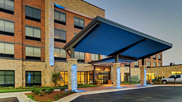A modern building with a covered entrance, brick walls, and large windows. - Holiday Inn Express & Suites Winston Salem Sw Clemmons by IHG (Clemmons)