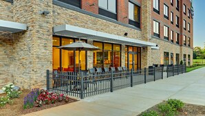 A modern building with a stone facade, outdoor seating area, and a fenced patio. - Holiday Inn Express & Suites Winston Salem Sw Clemmons by IHG (Clemmons)