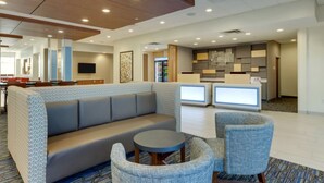 A modern hotel lobby with a seating area, a reception desk, and a kitchen in the background. - Holiday Inn Express & Suites Winston Salem Sw Clemmons by IHG (Clemmons)