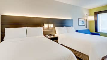 A hotel room with two beds, a nightstand with a phone and lamp, and a window with a view.
