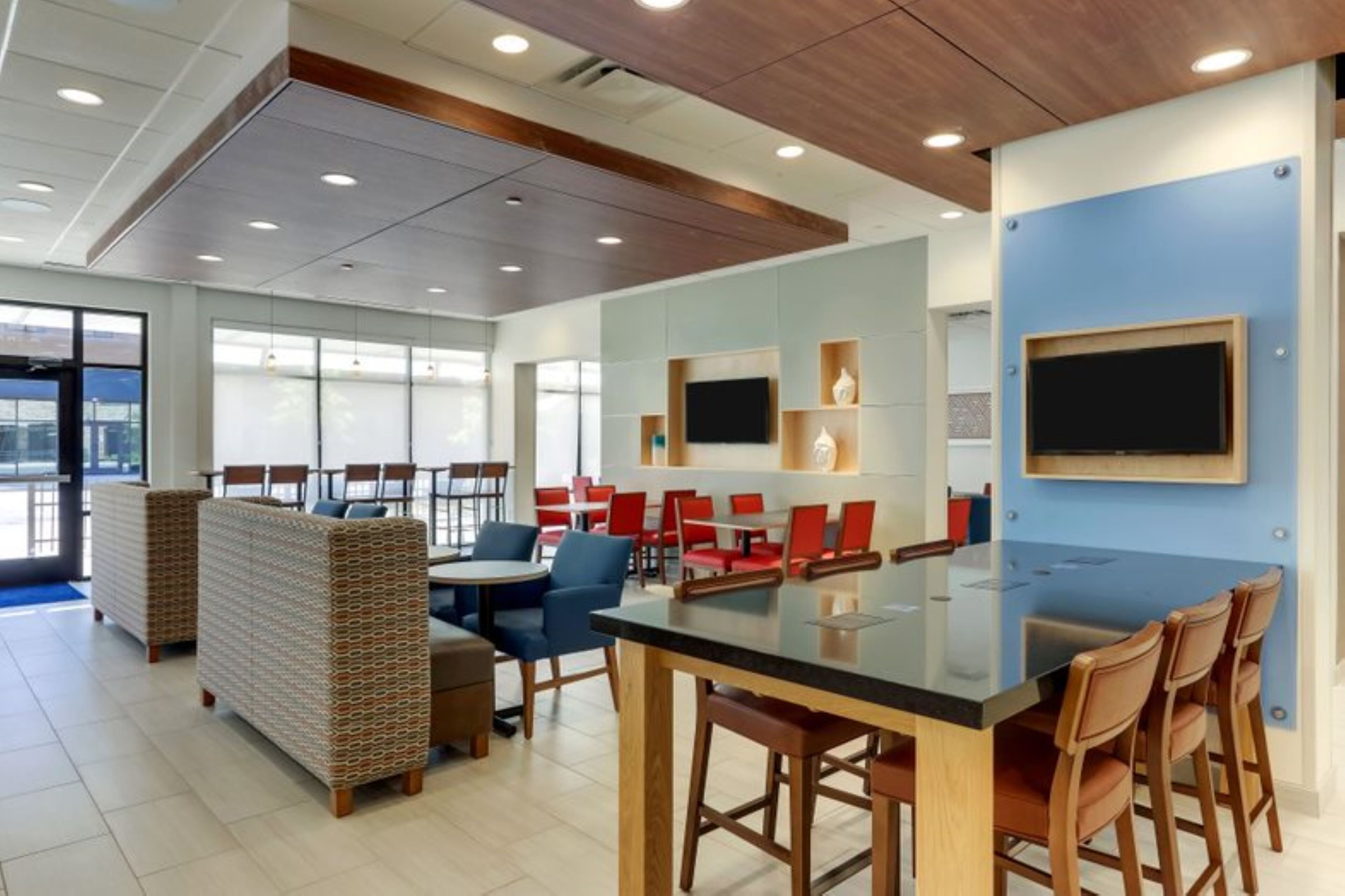 A modern conference room with a large glass table, wooden chairs, and a blue accent wall.