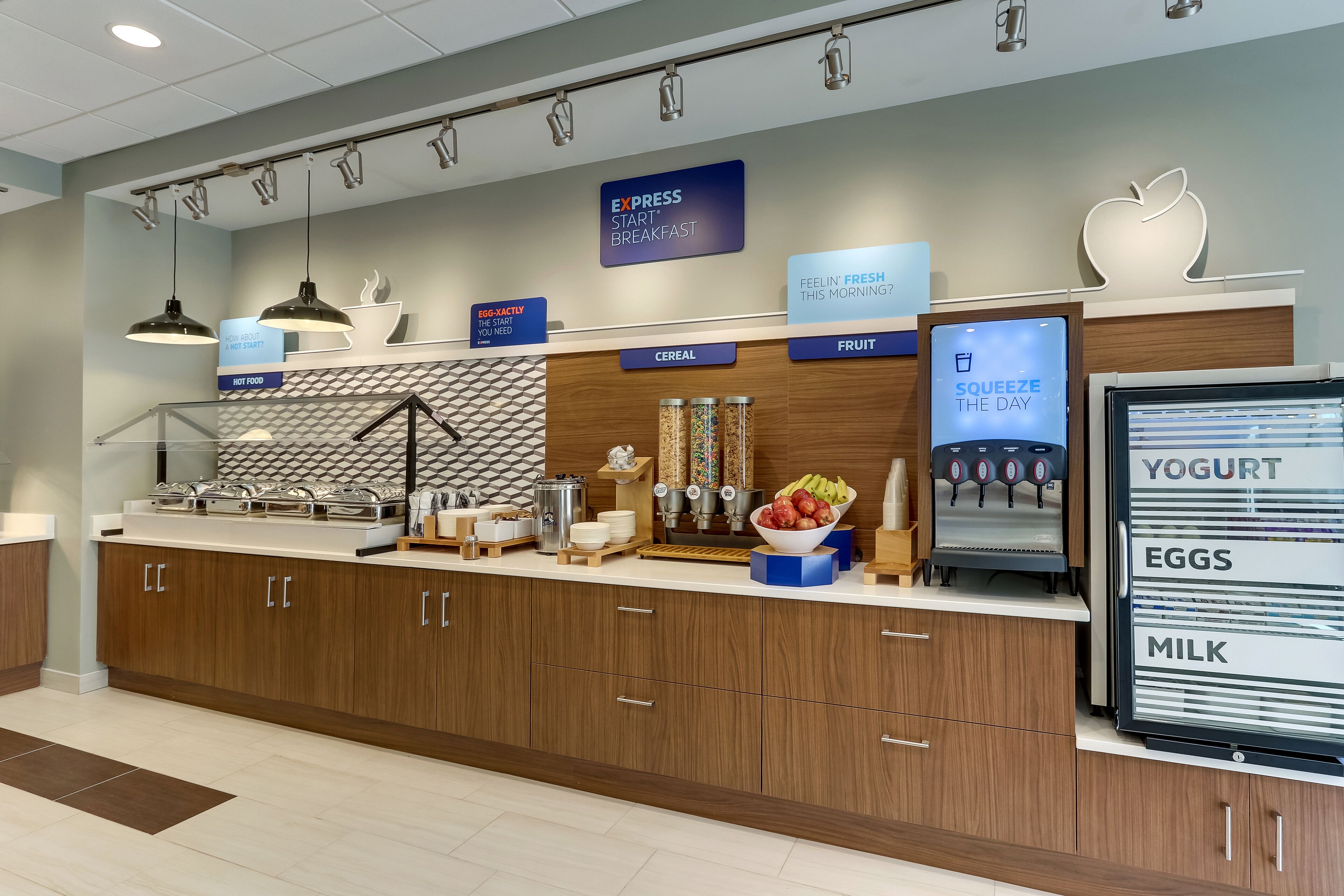 A modern breakfast area with a self-serve station, including options for cereal, fruit, yogurt, eggs, and milk.