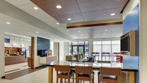 A modern kitchen area with a central island, bar stools, and a television mounted on the wall. - Holiday Inn Express & Suites Winston Salem Sw Clemmons by IHG (Clemmons)