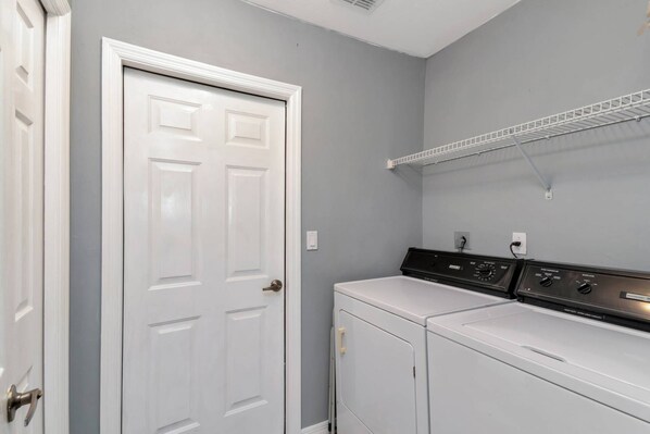 A laundry room with a white door, a washing machine, and a dryer. - Family Fun Getaway w/Beach Gear, Pool in Sun & WiFi ~1mi to Beach; Walk to Dining/Shops (Marco Island)