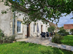 A stone building with a patio area, outdoor seating, and a garden.