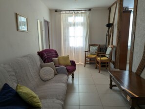 Een zithoek met een bank, twee fauteuils, een houten tafel en een vloerlamp.