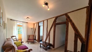 A spacious living room with a high ceiling, exposed wooden beams, a sofa set, a chair, a small table, and a television. - Farmhouse Retreat in Scenic Gâtinais - Spacious, Accessible & Eco-Friendly (Chailly-en-Gâtinais)