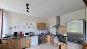 A modern kitchen with wooden cabinets, a stainless steel refrigerator, a microwave, a toaster, and a coffee maker. - Farmhouse Retreat in Scenic Gâtinais - Spacious, Accessible & Eco-Friendly (Chailly-en-Gâtinais)
