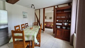 A dining area with a table set for four, wooden chairs, a buffet cabinet with dishes, and a painting on the wall. - Farmhouse Retreat in Scenic Gâtinais - Spacious, Accessible & Eco-Friendly (Chailly-en-Gâtinais)