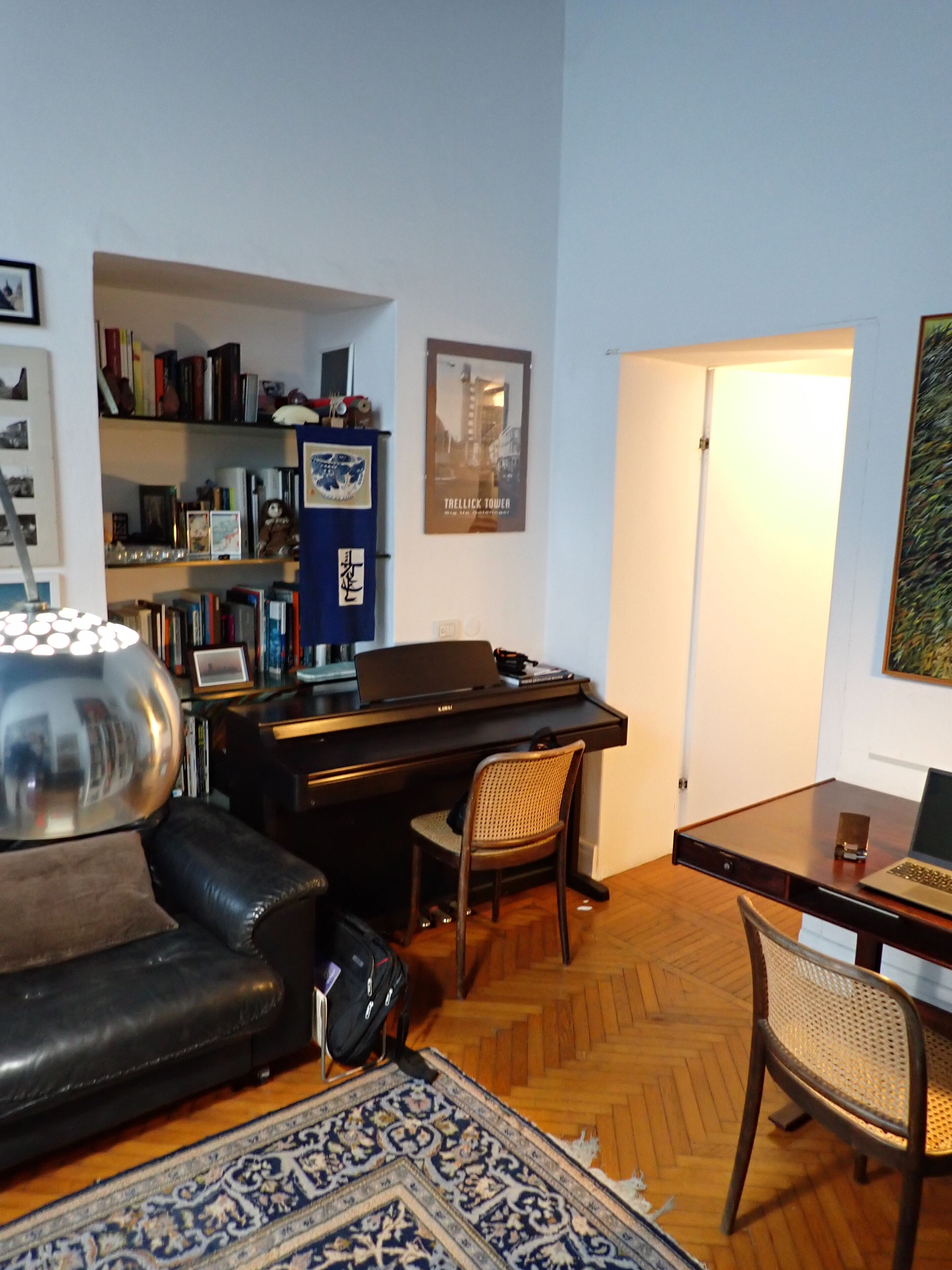 A living room with a piano, a sofa, a coffee table, and a bookshelf.