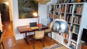 A room with a wooden desk, a laptop, a chair, a bookshelf, and a large painting on the wall. - Brera Boutique Unit (milano)