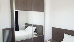 Une chambre d’hôtel moderne équipée d’un lit, d’une table de chevet et d  ’une armoire intégrée.