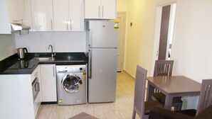 Une cuisine compacte équipée d’un lave-linge, d’un réfrigérateur et d’un coin repas avec une table et des chaises.
