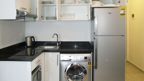 Une cuisine de taille réduite équipée d’un lave-linge, d’un évier et d’un réfrigérateur.