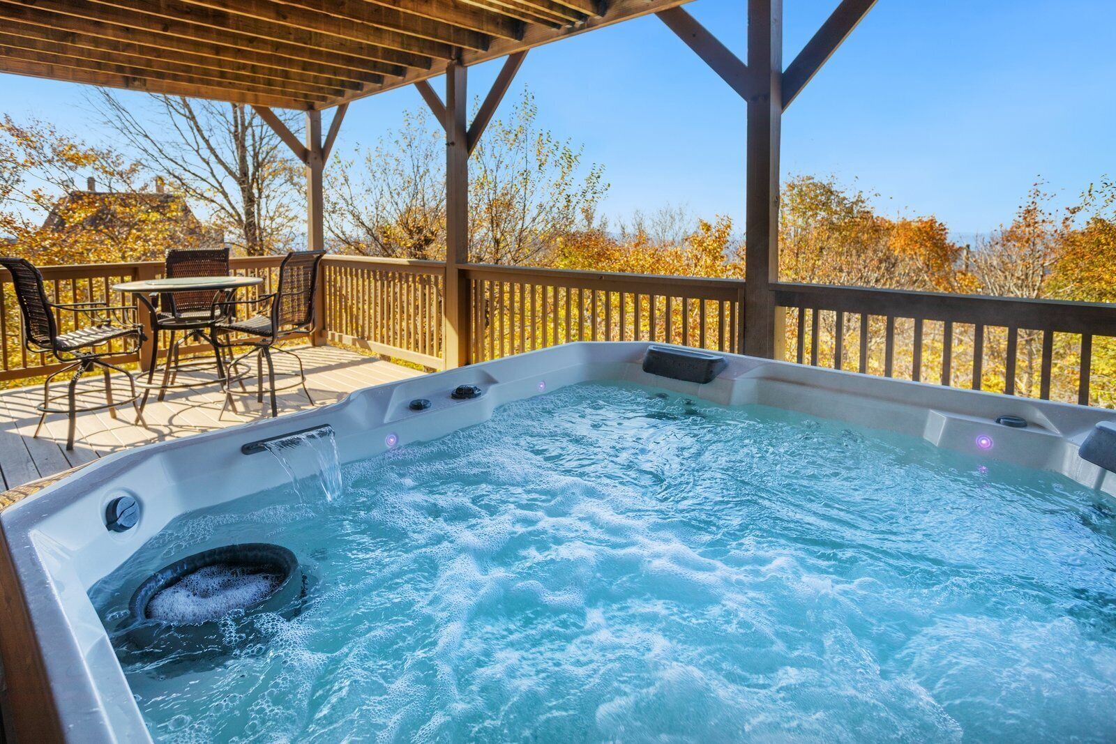 Un bain à remous installé sous une pergola en bois, avec une table et des chaises de patio.