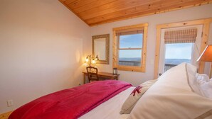 Quarto com cama, escrivaninha, cadeira e janela com vista.