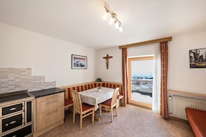 A kitchen with a table and chairs, a bench, a radiator, and a window with a view.