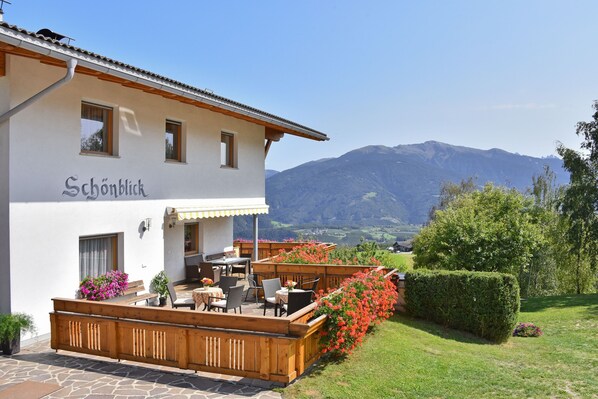 A building with a sign 'Schonblick' and a patio area with tables and chairs.