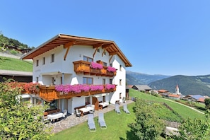 Un immeuble à deux étages doté de balcons, d’un espace extérieur aménagé pour s’asseoir et offrant une vue sur les montagnes.